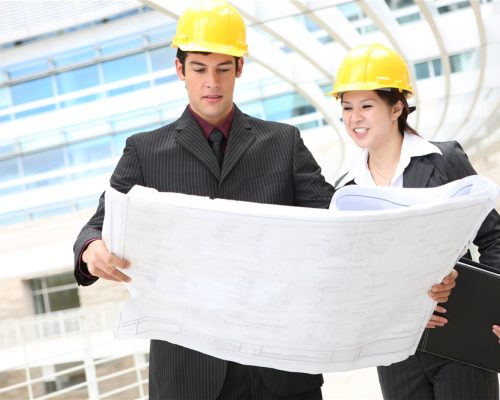 Attractive man and woman architects on building construction site